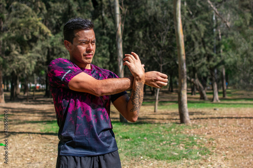 latin fit man doing arm stretching exercises. Getting ready and warming up before running outside.