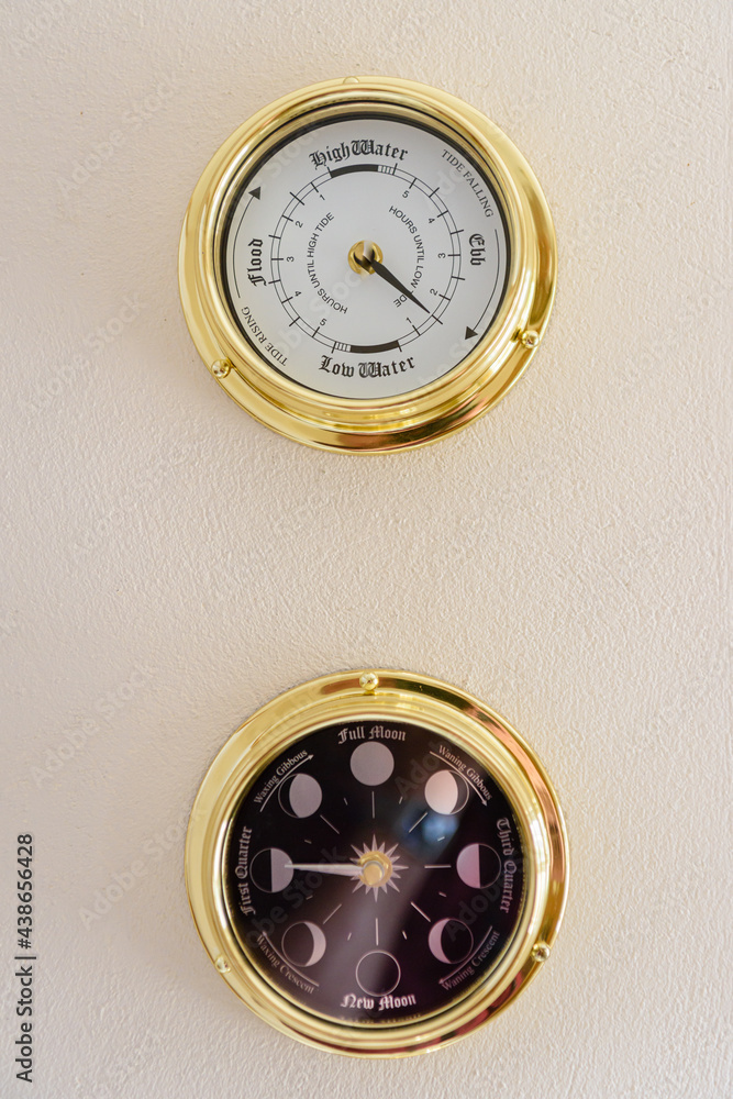 Brass tidal clock and moon phase clock on a wall Brass tidal clock and moon phase clock on a wall