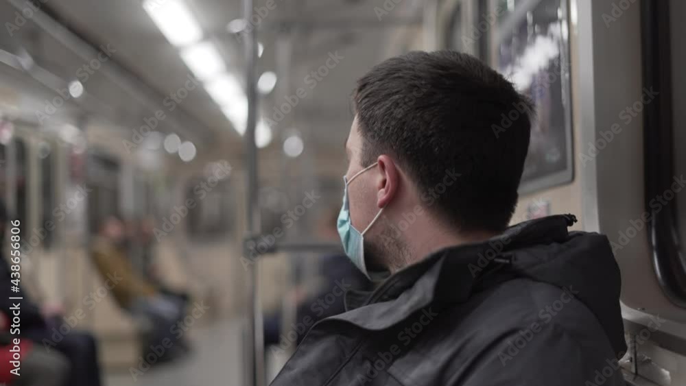 Man in medical mask riding in subway car. Safety in public place while epidemic of covid-19. Pandemic flu. Human masked 2019-ncov. Train metro tube. Prevent infection. New normal. Social distancing Man in medical mask riding in subway car. Safety in public place while epidemic of covid-19. Pandemic flu. Human masked 2019-ncov. Train metro tube. Prevent infection. New normal. Social distancing