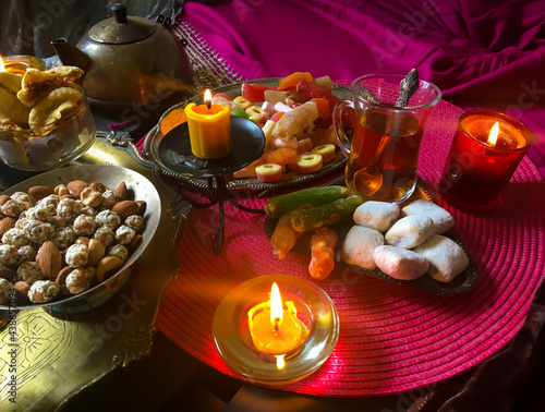 A table with Turkish tea with lale, oriental sweets, rahad delight, a mix of various nuts using copper dishes and bright fabrics. photo