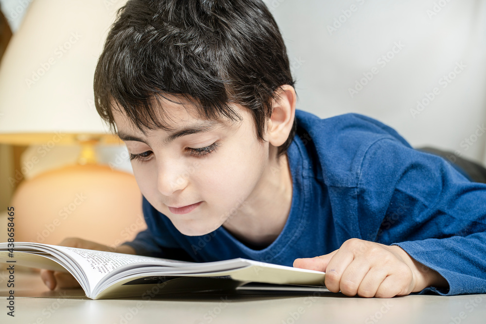 Cute little boy reading book under a tent at home alone Cute little boy reading book under a tent at home alone