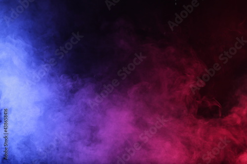 Artifiacial magic smoke in red-blue light on black background