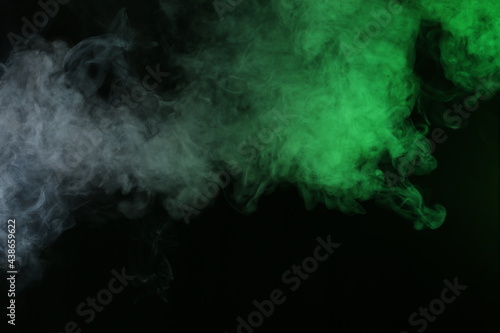 Artificial smoke in grey-green light on black background