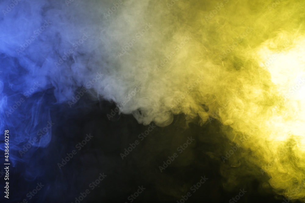 Artificial magic smoke in blue yellow light on black background Artificial magic smoke in blue yellow light on black background