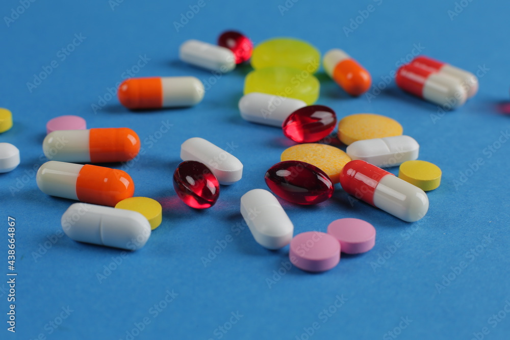 Multicolored medical pills of various shapes on a blue background Multicolored medical pills of various shapes on a blue background