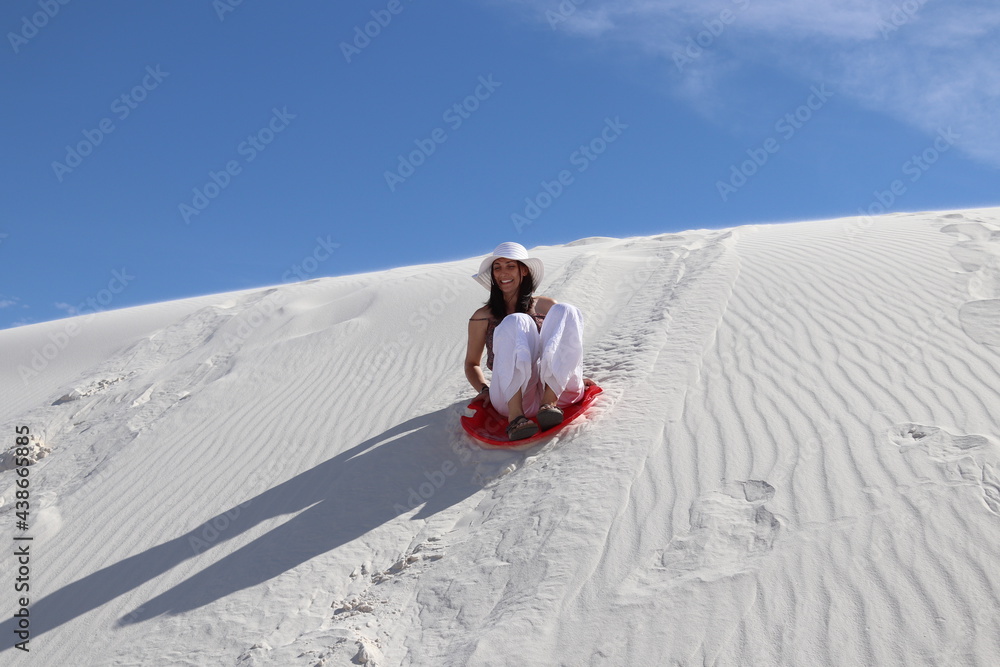 woman sliding down dune on sled