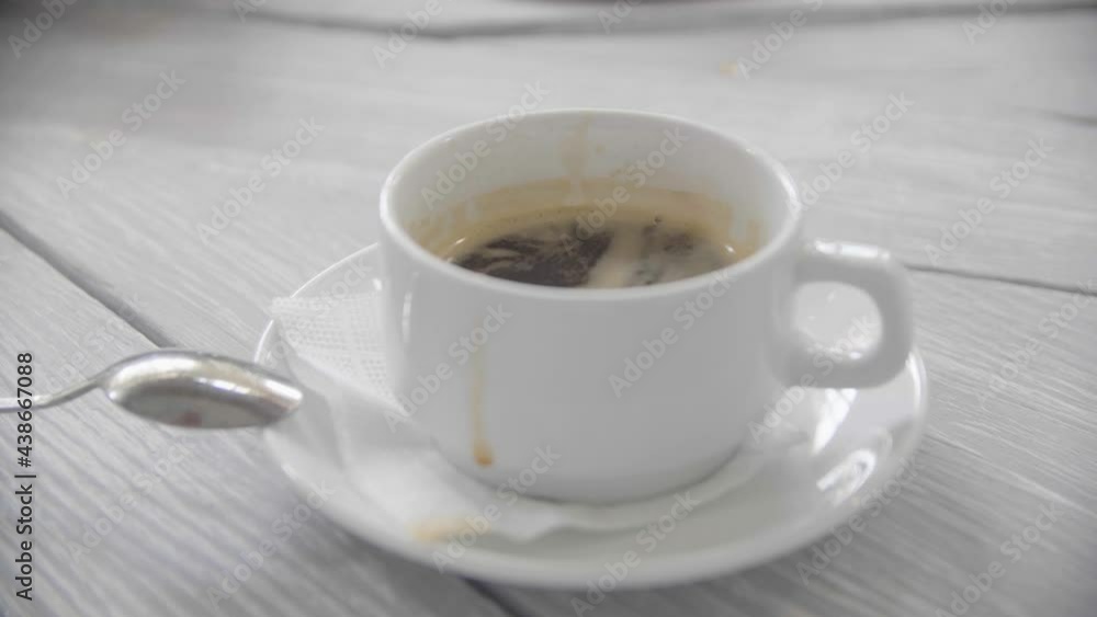 A young caring housewife is stirring sugar in a cup with hot aromatic coffee. Close-up of a young attractive woman's hand she is stirring sugar in a cup with aromatic natural coffee. A young caring housewife is stirring sugar in a cup with hot aromatic coffee. Close-up of a young attractive woman's hand she is stirring sugar in a cup with aromatic natural coffee.