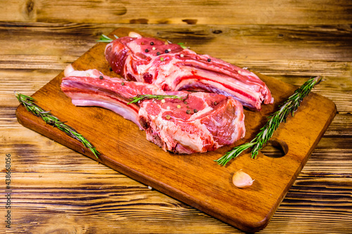 Raw ribeye steak, spices, rosemary and garlic on cutting board