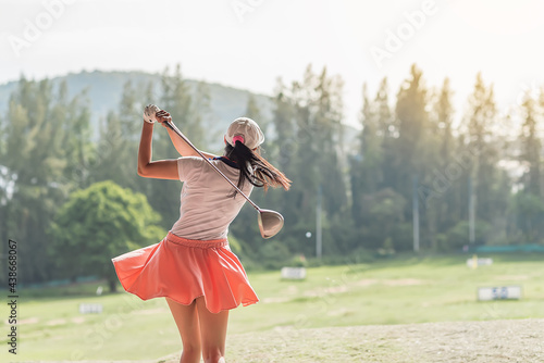 young professional female golf player hit sweeping and keep golf course doing golf swing,she does exercise for relax time