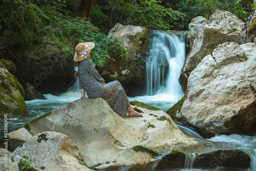 young woman with hat enjoying in nature, clean river oasis in the forest photo