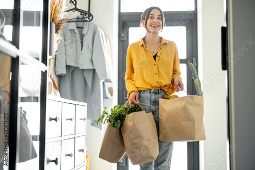Foto Woman comes home with bags full of fresh groceries, shopping healthy food in eco-packaging