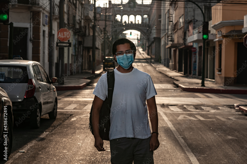 Portrait of a boy walking in empty streets of a city with a medical mask.