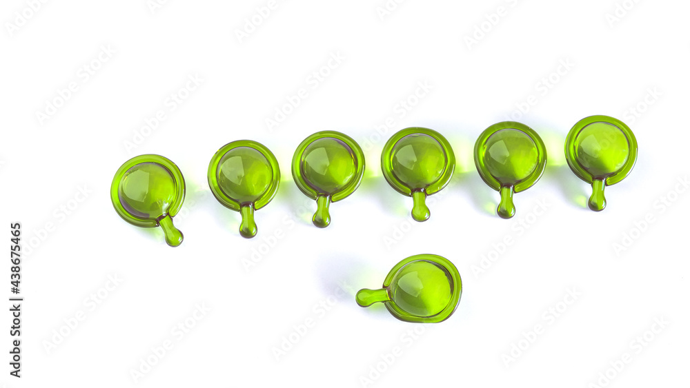 Vitamin serum capsule green color for repairing skin on background.