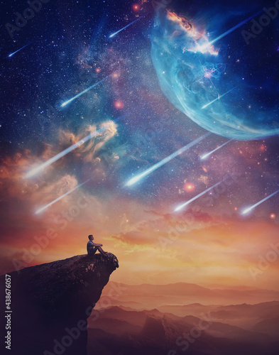 Lone person on the peak of a cliff admiring a wonderful space phenomenon. Fantastic scenery with falling stars and colorful nebulas above the sunset. Inspirational imaginary landscape  mystery view