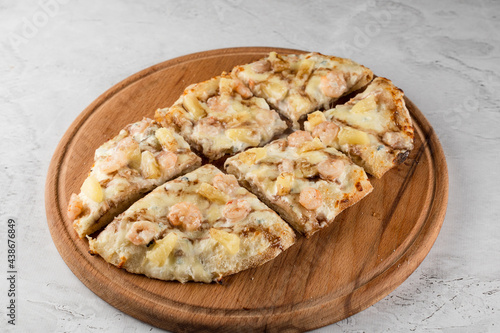 Pinsa romana with shrimps and pineapple on wooden plate on white background. Seafood scrocchiarella. photo