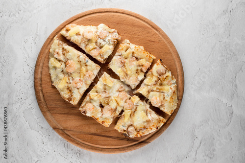 Pinsa romana with shrimps and pineapple on wooden plate on white background. Seafood scrocchiarella.