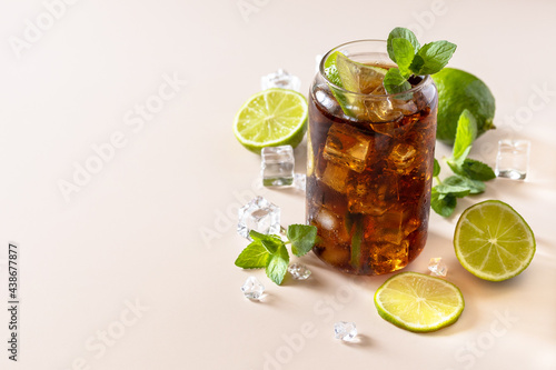 Cuba Libre alcoholic drink, Cola with ice cubes or lemonade on a pastel brown background. Copy space.