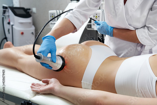 Ultrasound cavitation body contouring treatment. Woman getting anti-cellulite and anti-fat therapy in beauty salon photo