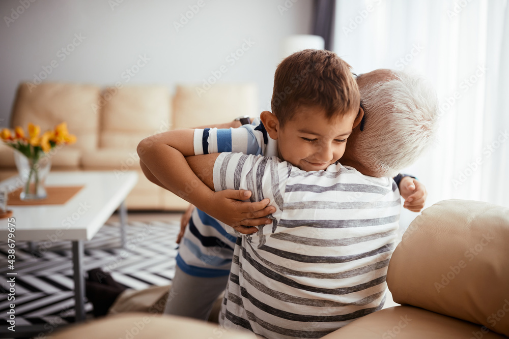 Happy boy enjoying in grandfather's embrace while spending time together at home. Happy boy enjoying in grandfather's embrace while spending time together at home.