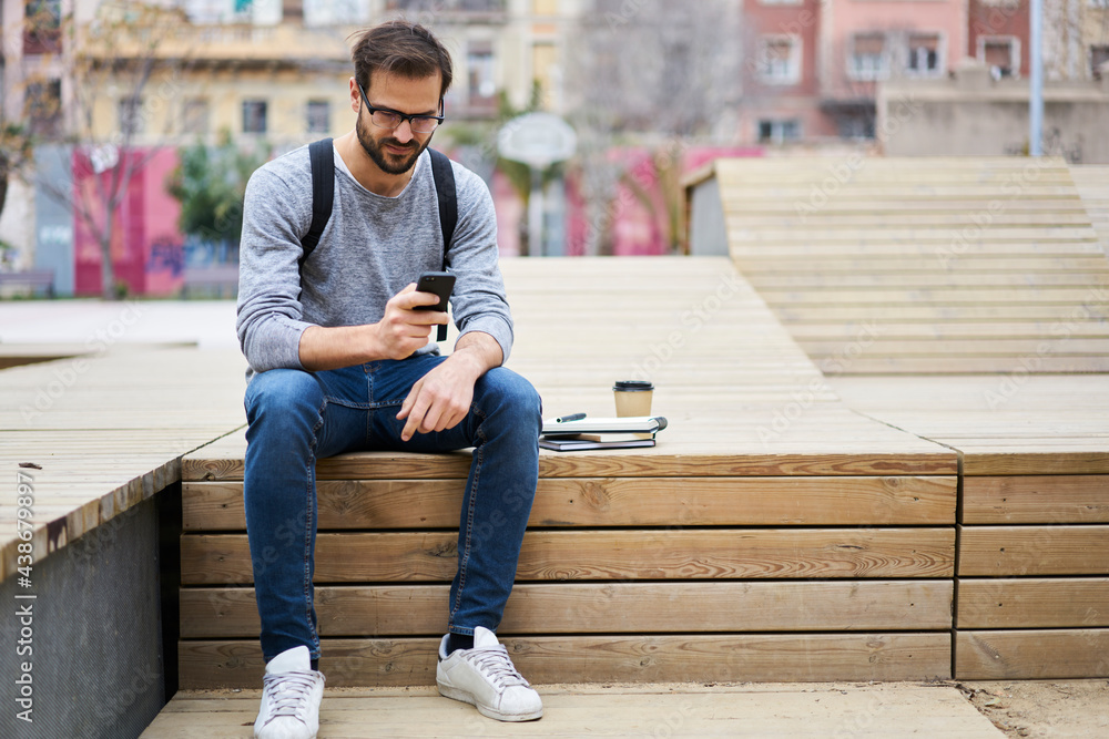 Busy male freelancer sitting with phone outside