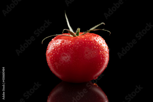 Red tomato with water drops on black
