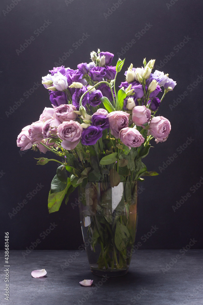 Roses in a glass vase on a black background. Dark photo. Roses in a glass vase on a black background. Dark photo.