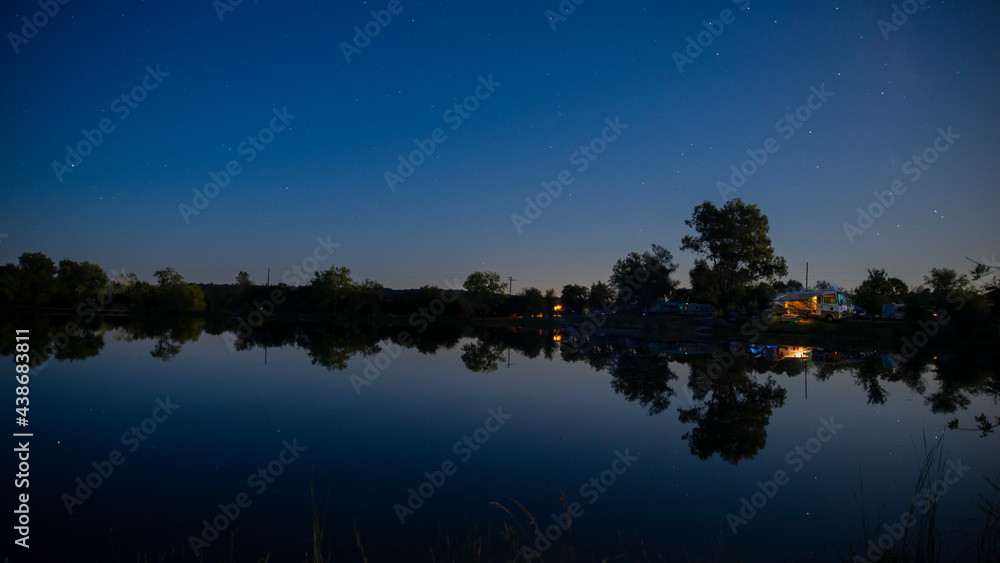 Camping in a motorhome a long side the waters edge at night under a starry sky
