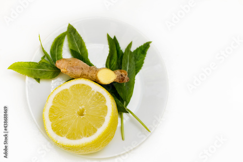 healthy food and drink tea with lemon, mint and ginger in a transparent jug and on a white plate