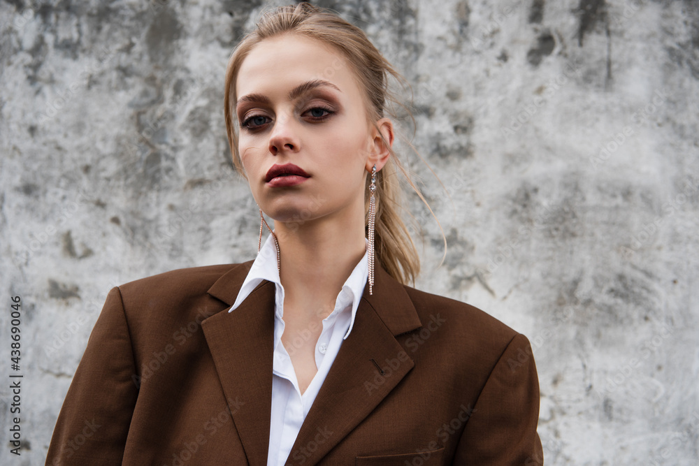 young model in trendy brown blazer posing near concrete wall young model in trendy brown blazer posing near concrete wall
