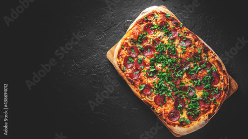 Pepperoni Pizza with Mozzarella cheese, salami, Tomato sauce, pepper, Spices. Italian pizza on Dark grey black slate background