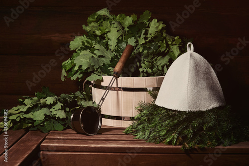 interior of a traditional steam sauna banya with wooden tub, water ladle, hat and bath brooms on a bench photo