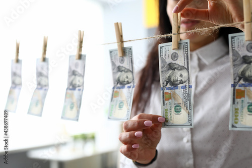 Female hands taking 100 dollar bill off clothes line