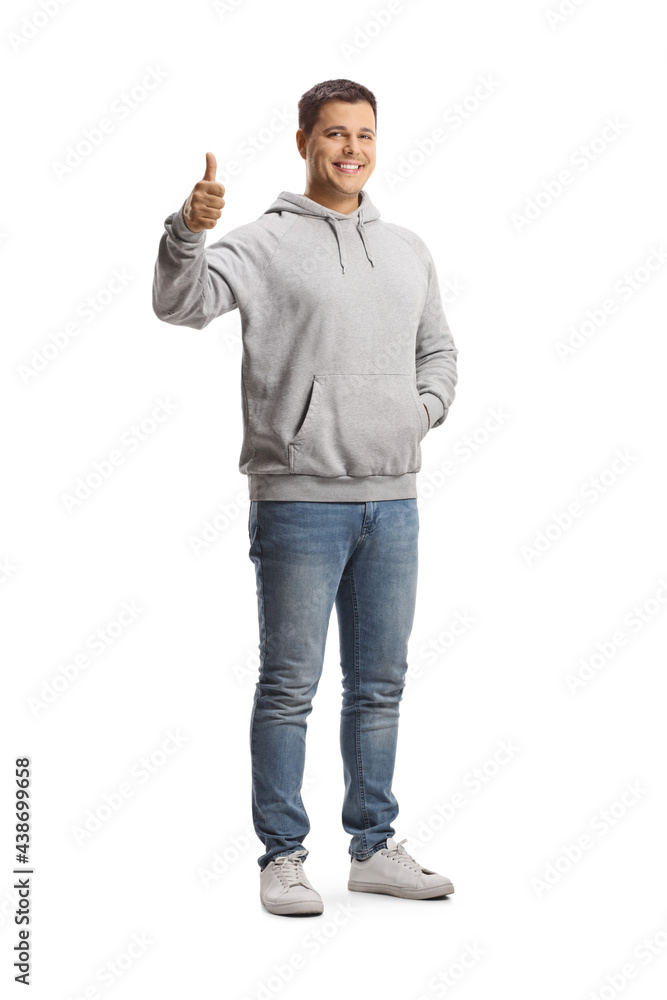 Full length portrait of a young man in a gray hoodie and jeans showing thumbs up Full length portrait of a young man in a gray hoodie and jeans showing thumbs up