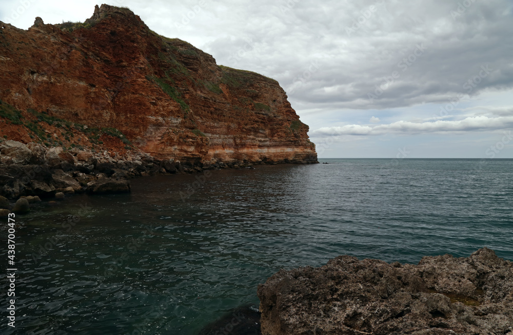 Red cliffs on the sea in a cloudy day