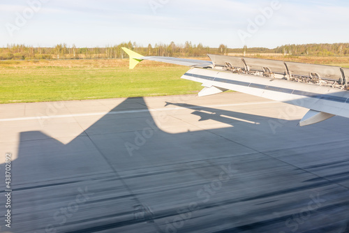 View of airplane wing, Shadow of the plane on the ground during landing, seen from the plane window.