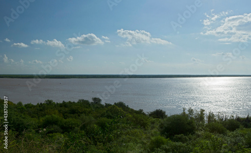 Aerial view of the green tropical jungle and river at sunrise. The bright sun reflection in the surface of the water.