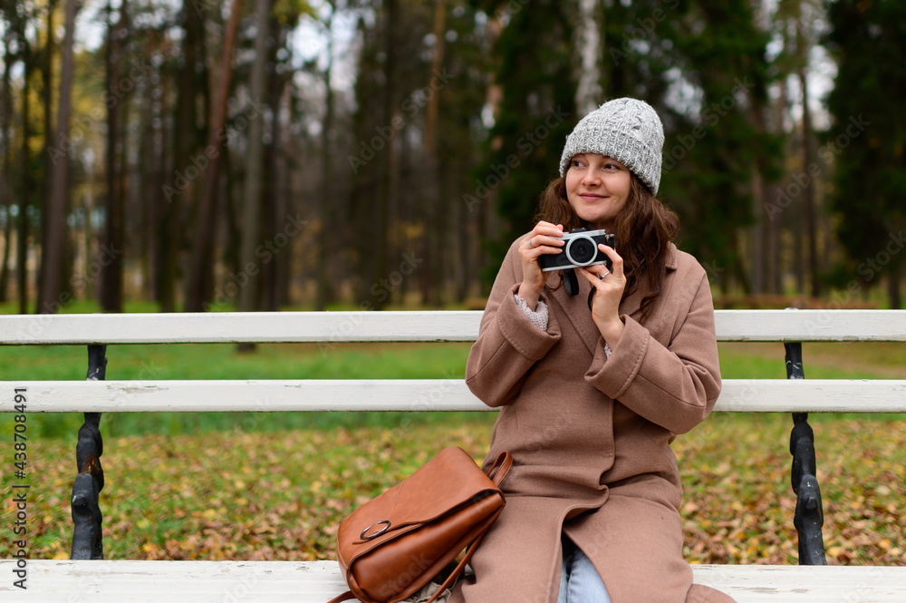 Young photographer woman sitting on a bench in the park and looking for a shoot Young photographer woman sitting on a bench in the park and looking for a shoot