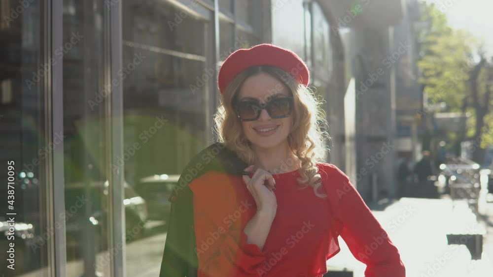 Luxurious young blonde woman stands on the street in the city and with a smile throws a jacket over her shoulder. Stylish beauty smiles to the camera Luxurious young blonde woman stands on the street in the city and with a smile throws a jacket over her shoulder. Stylish beauty smiles to the camera