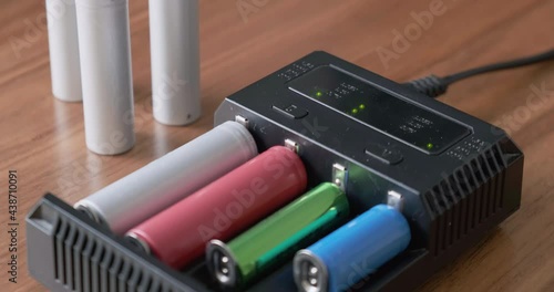 Rechargeable batteries of various sizes charging in a multi charger with blinking green leds. Lithium-Ion, Nickel–metal hydride, NiMH. photo