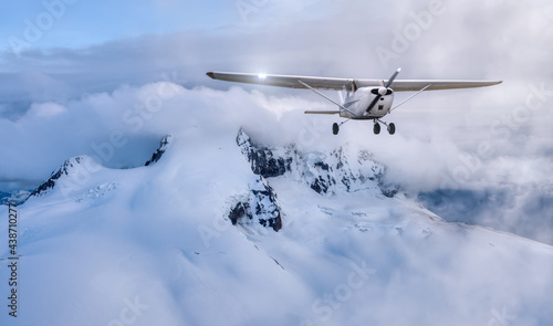 Airplane flying near the Beautiful Canadian Mountain Nature Landscape. Adventure Composite. Cloudy Sunset Sky. Background from near Squamish and Vancouver, British Columbia, Canada.