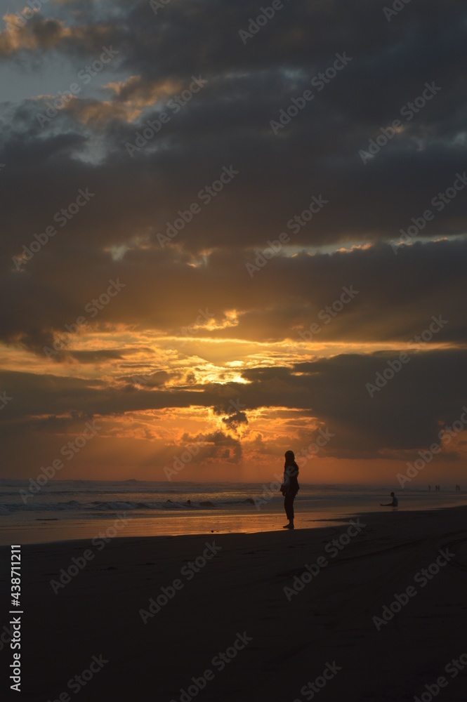 a person walking on the beach at sunset