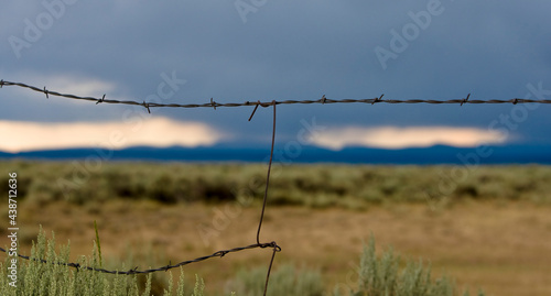 Barbed wire fence with a storm approaching during adventures of The West in Robertson, Wyoming and the ranches in the Bridger Valley.  photo