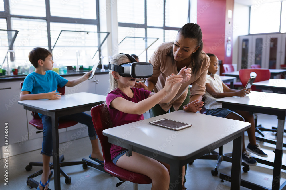 African american female teacher teaching caucasian girl to use vr headset in the class at school African american female teacher teaching caucasian girl to use vr headset in the class at school