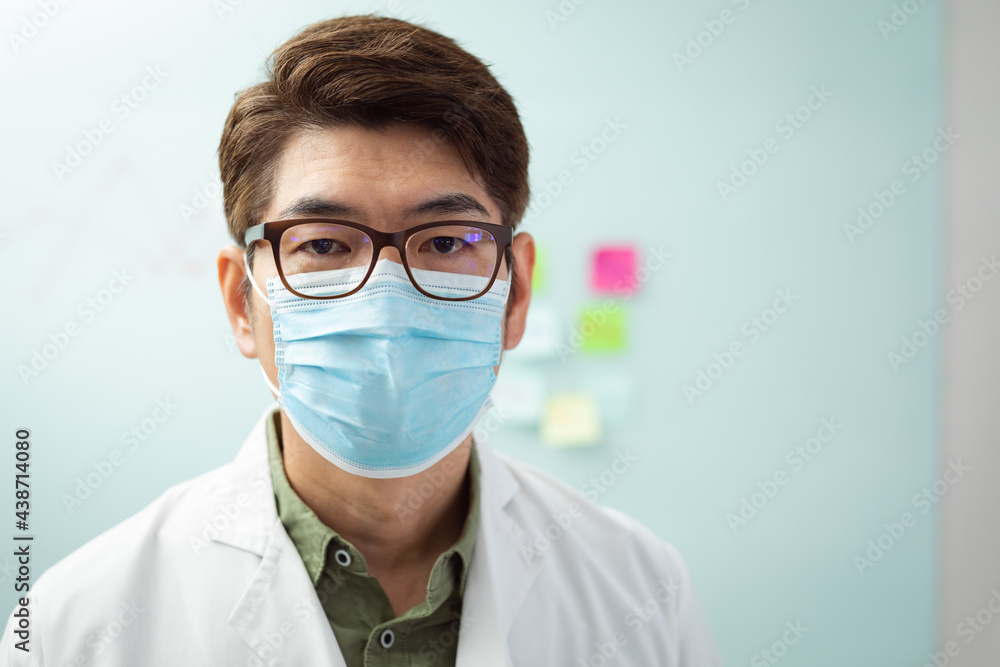 Portrait of asian male doctor wearing face mask sitting in hospital office looking to camera Portrait of asian male doctor wearing face mask sitting in hospital office looking to camera