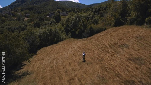 Aerial view of a mountain biker going downhill while crossing a meadow near Costa, Emilia-Romagna, Italy. photo