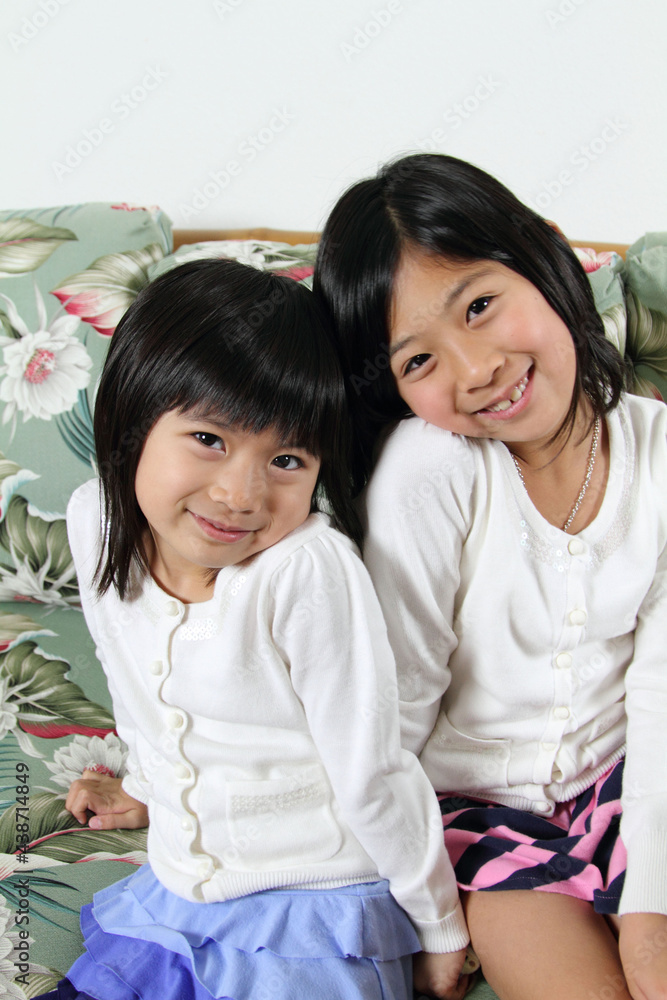 Two cute Japanese sisters smiling at the camera Two cute Japanese sisters smiling at the camera
