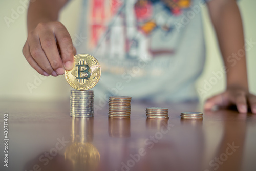 Young boy holding bitcoin with selective focus on the coin, Cryptocurrency and modern finance concept.