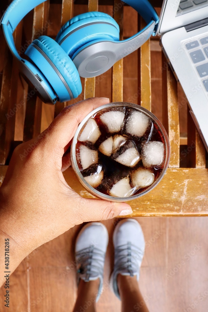 Cola drink with ice cubes and notebook with headphone work from home concept Cola drink with ice cubes and notebook with headphone work from home concept