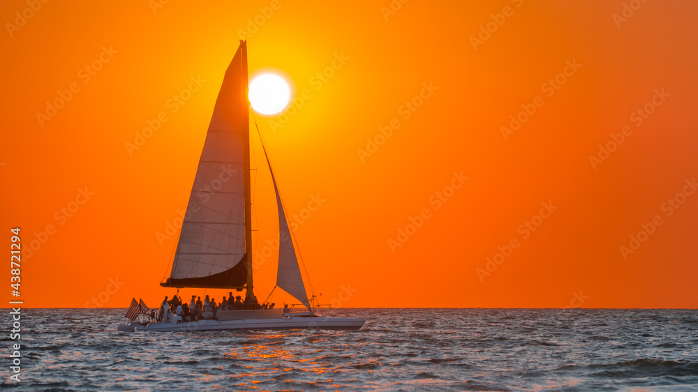 Sailboat. Beautiful seascape with sail boat or luxury yacht on horizon. Ocean sunset and red sky. Summer vacation in Florida. Good for travel agency, billboard or post card. Photo with copy space.