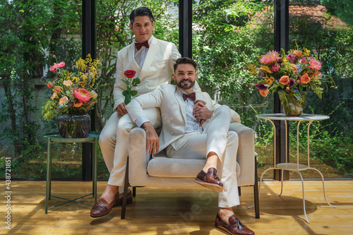 LGBTQ gay couple sitting together in living room in wedding ceremony photo